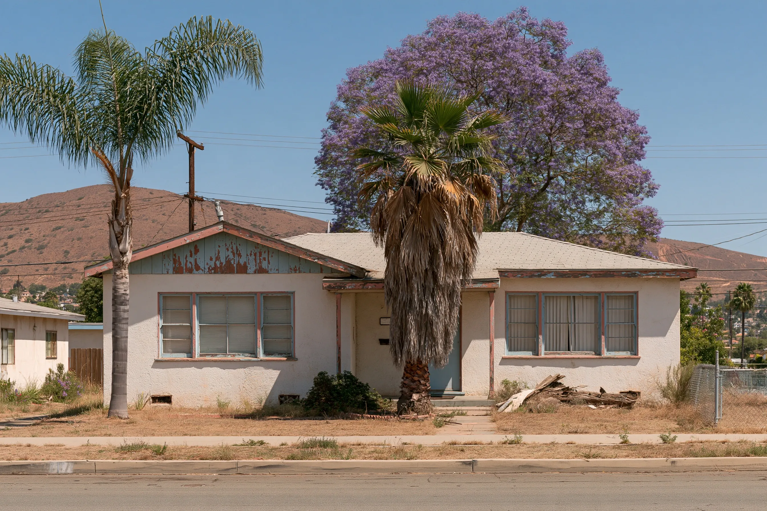 1950s Southern California stucco bungalow with painted wood eaves, trim and windows under palm and jacaranda trees